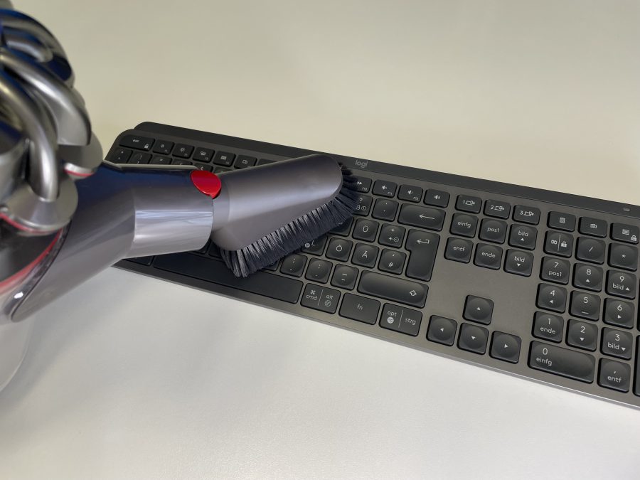 Entfernen Sie mit einem Handstaubsauger den groben Schmutz von Ihrer Tastatur.